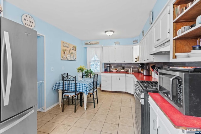 kitchen with decorative backsplash, appliances with stainless steel finishes, custom range hood, light tile patterned floors, and white cabinetry