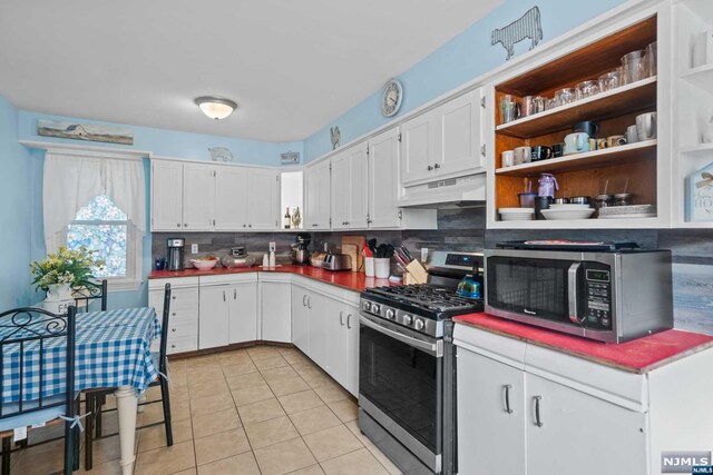 kitchen with white cabinets, appliances with stainless steel finishes, decorative backsplash, and light tile patterned flooring