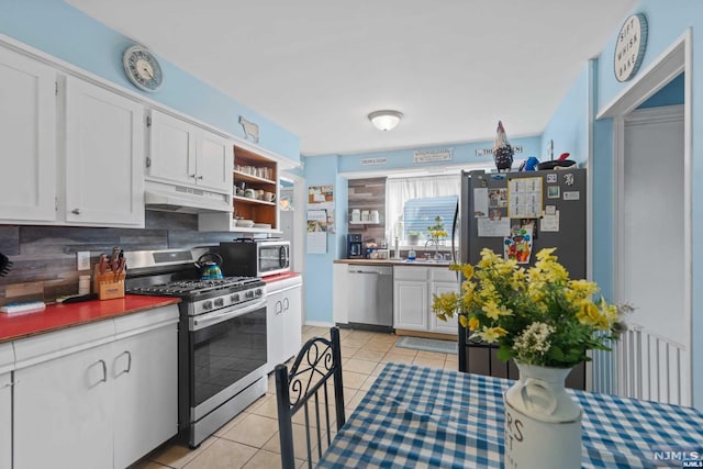 kitchen with white cabinets, appliances with stainless steel finishes, tasteful backsplash, and light tile patterned floors