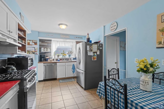 kitchen with white cabinets, appliances with stainless steel finishes, sink, and light tile patterned flooring