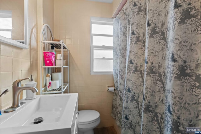 bathroom with a wealth of natural light, tile walls, and toilet