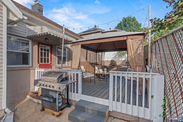 wooden terrace with a gazebo and a grill