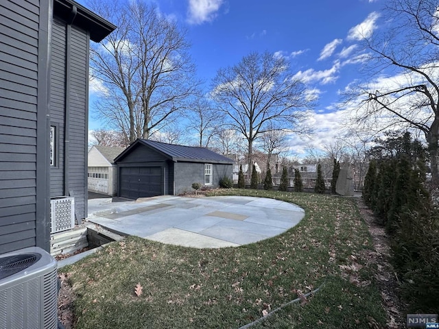 view of yard with a garage, central AC, and an outdoor structure