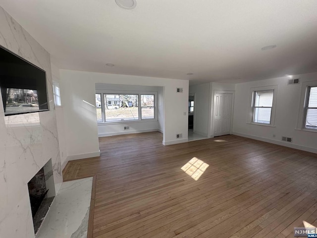 unfurnished living room with wood-type flooring, a wealth of natural light, and a premium fireplace