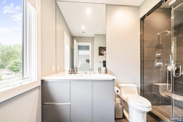 bathroom with walk in shower, vanity, and toilet