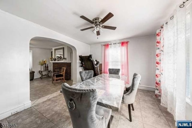 dining room with ceiling fan, light tile patterned floors, and a fireplace