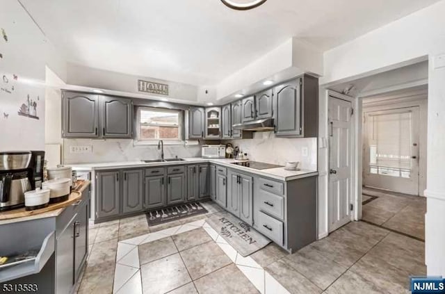 kitchen featuring decorative backsplash, gray cabinetry, black electric cooktop, sink, and light tile patterned flooring