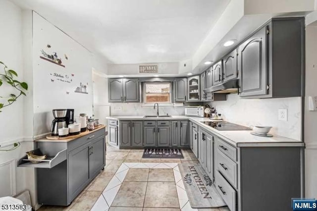 kitchen with gray cabinetry, black electric stovetop, light tile patterned floors, and sink