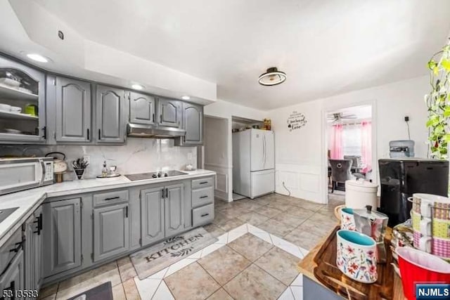 kitchen featuring gray cabinetry, decorative backsplash, and white appliances