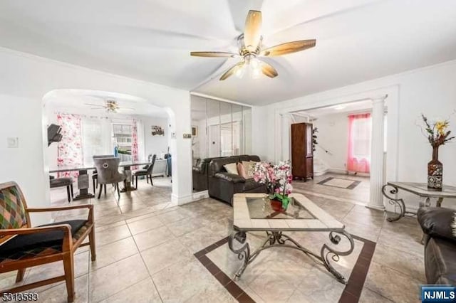 tiled living room featuring ceiling fan and ornamental molding