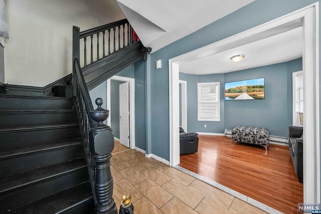 staircase with hardwood / wood-style floors and baseboard heating