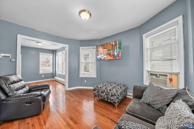 living room with hardwood / wood-style floors, plenty of natural light, cooling unit, and baseboard heating