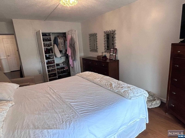 bedroom with a closet, a textured ceiling, and hardwood / wood-style flooring