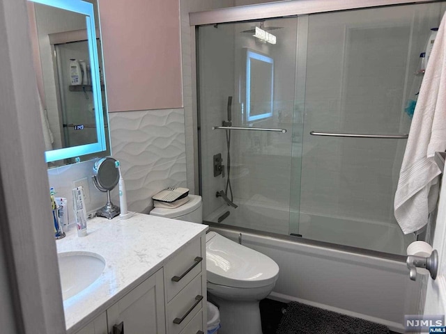 full bathroom with vanity, toilet, and bath / shower combo with glass door