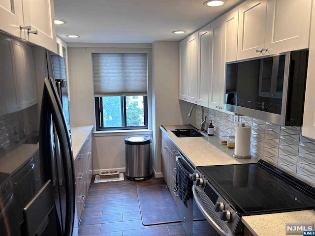 kitchen featuring light stone countertops, sink, dark wood-type flooring, stainless steel appliances, and white cabinets