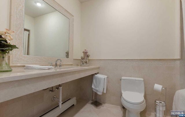 bathroom with toilet, tile walls, and sink