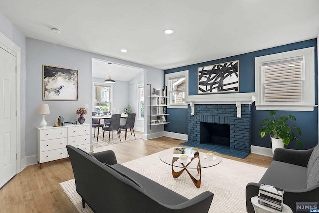 living room with light hardwood / wood-style floors and a brick fireplace