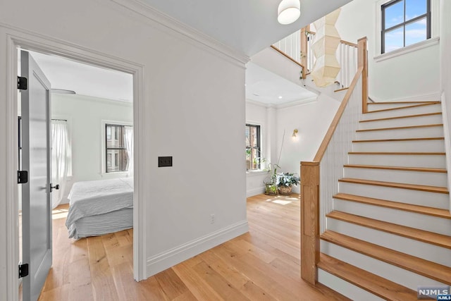 entryway featuring crown molding, a healthy amount of sunlight, and light wood-type flooring