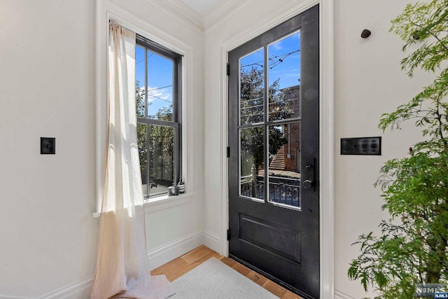 foyer entrance with light hardwood / wood-style floors and ornamental molding