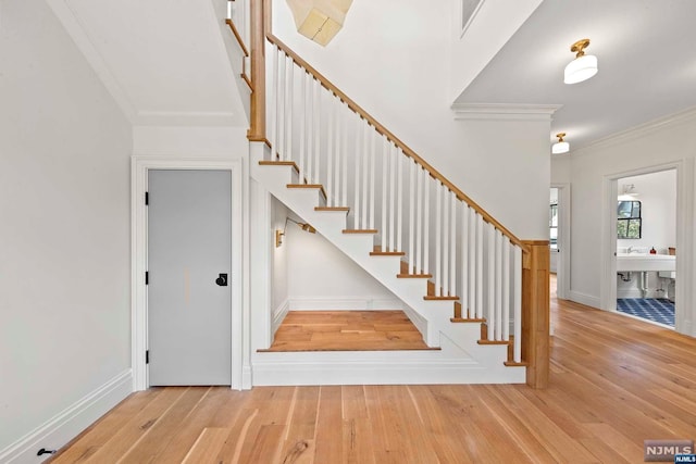 stairway with crown molding and hardwood / wood-style floors