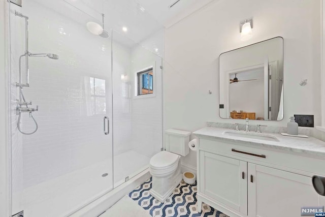 bathroom with ceiling fan, tile patterned flooring, toilet, vanity, and a shower with shower door