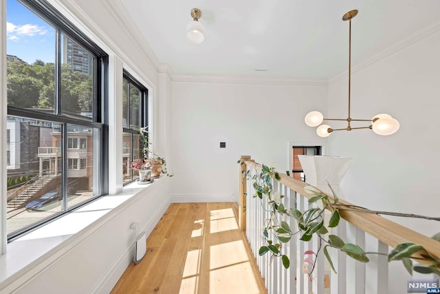 hall featuring light wood-type flooring, an inviting chandelier, and ornamental molding