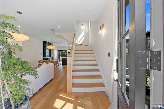 staircase with wood-type flooring and crown molding