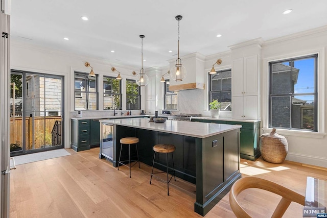 kitchen featuring a kitchen breakfast bar, ornamental molding, decorative light fixtures, light hardwood / wood-style floors, and a kitchen island