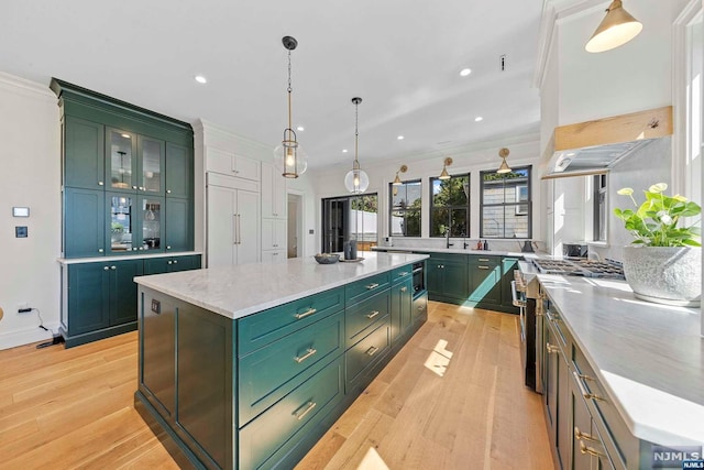 kitchen featuring light wood-type flooring, a center island, decorative light fixtures, and crown molding