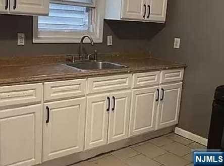 kitchen with white cabinetry, sink, and light tile patterned flooring