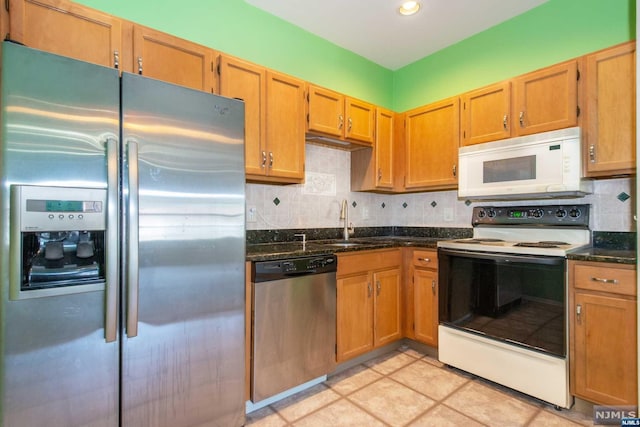 kitchen featuring tasteful backsplash, dark stone countertops, sink, and stainless steel appliances