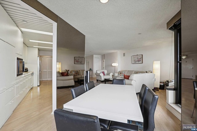 dining space with a textured ceiling and light wood-type flooring