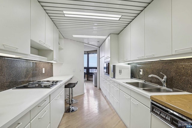 kitchen with dishwashing machine, white cabinetry, sink, and gas cooktop