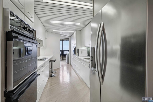 kitchen featuring white cabinets, light wood-type flooring, and stainless steel appliances