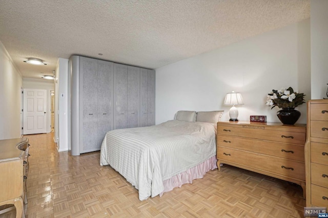 bedroom featuring a closet, light parquet floors, and a textured ceiling