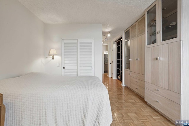 bedroom featuring a closet, a textured ceiling, and light parquet floors