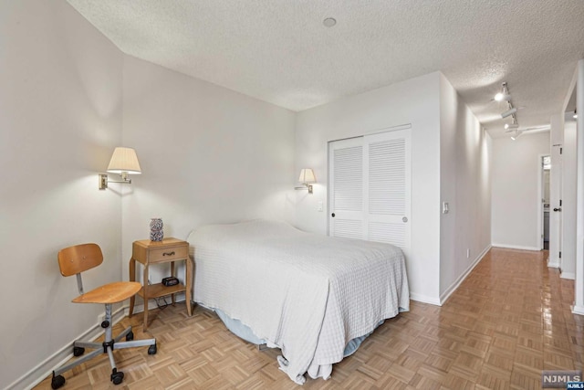 bedroom featuring a closet, light parquet flooring, and a textured ceiling