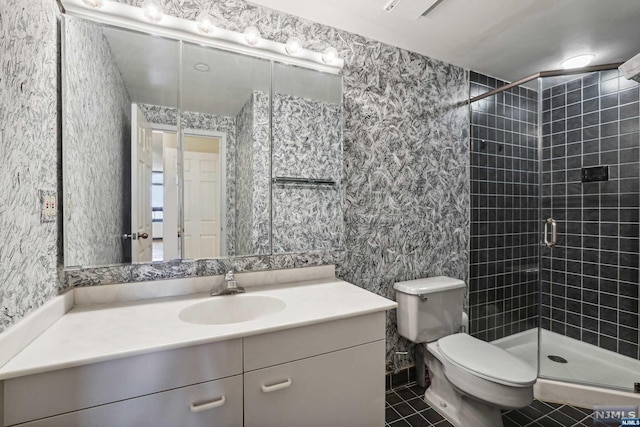 bathroom featuring tile patterned flooring, vanity, toilet, and walk in shower