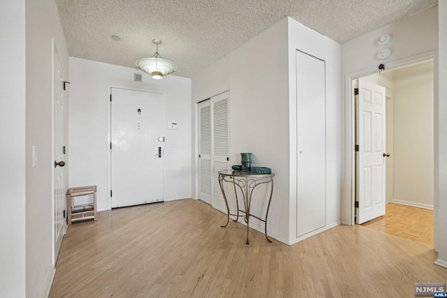 foyer featuring a textured ceiling and light hardwood / wood-style flooring