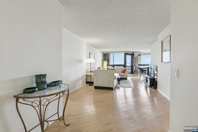 living room featuring expansive windows, light hardwood / wood-style floors, and a textured ceiling