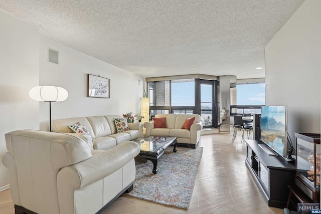 living room featuring light hardwood / wood-style flooring, expansive windows, and a textured ceiling