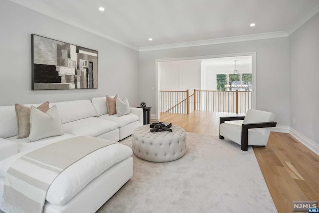 living room featuring a notable chandelier, wood-type flooring, and ornamental molding