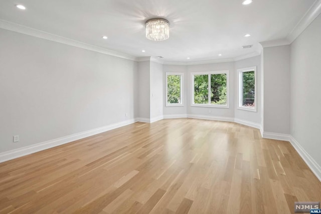 spare room with an inviting chandelier, ornamental molding, and light hardwood / wood-style flooring