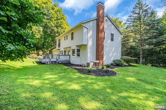 view of side of home with a lawn, a wooden deck, and central air condition unit