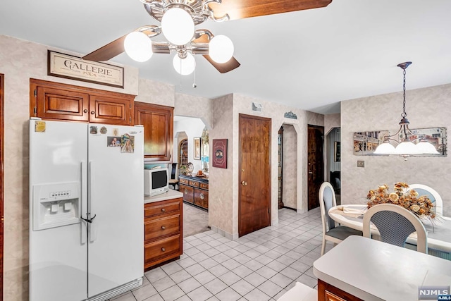 kitchen with light tile patterned floors, decorative light fixtures, white fridge with ice dispenser, and ceiling fan