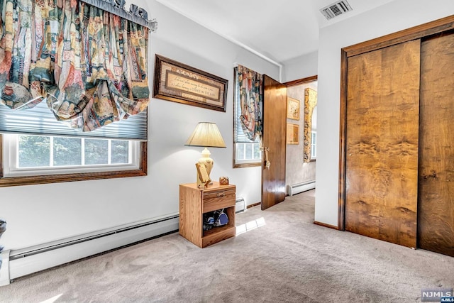 hallway featuring light carpet and a baseboard heating unit