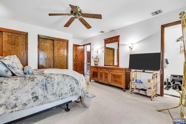 carpeted bedroom with ceiling fan and multiple closets