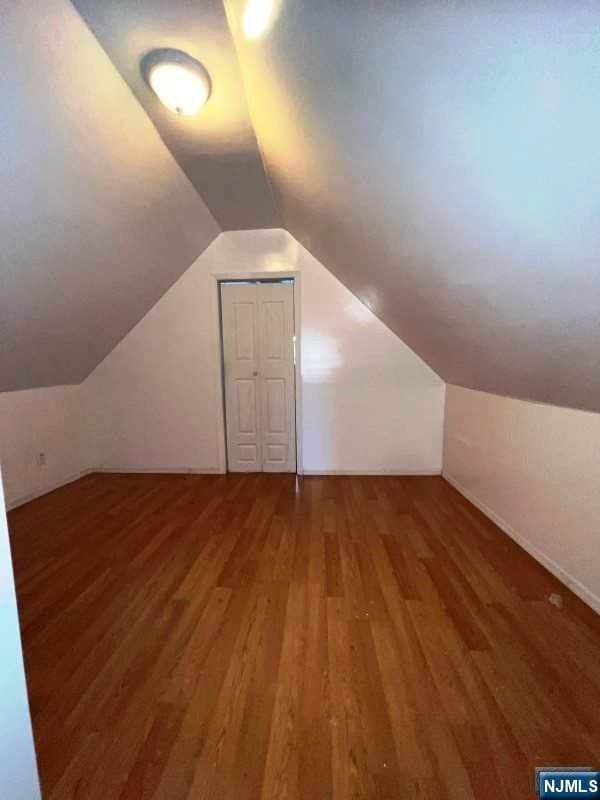 bonus room with dark hardwood / wood-style floors and vaulted ceiling