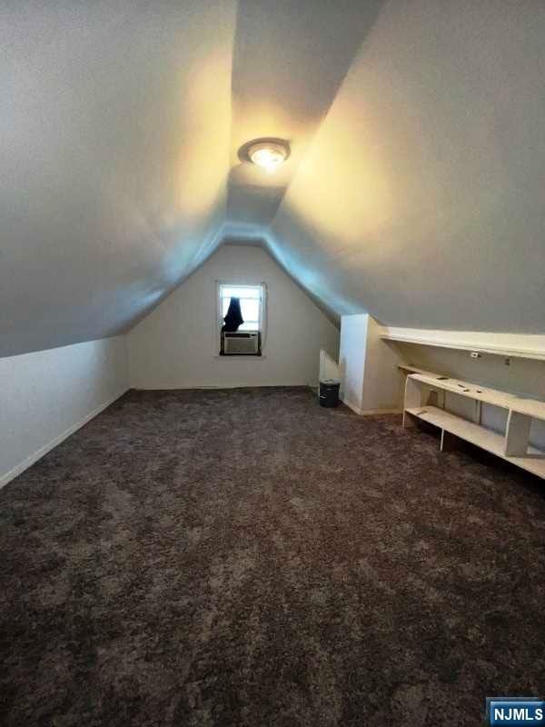 bonus room featuring cooling unit, vaulted ceiling, and dark carpet