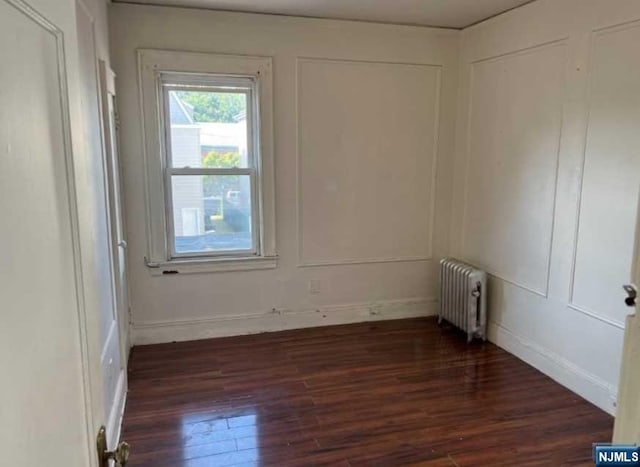 unfurnished room with dark hardwood / wood-style floors and radiator